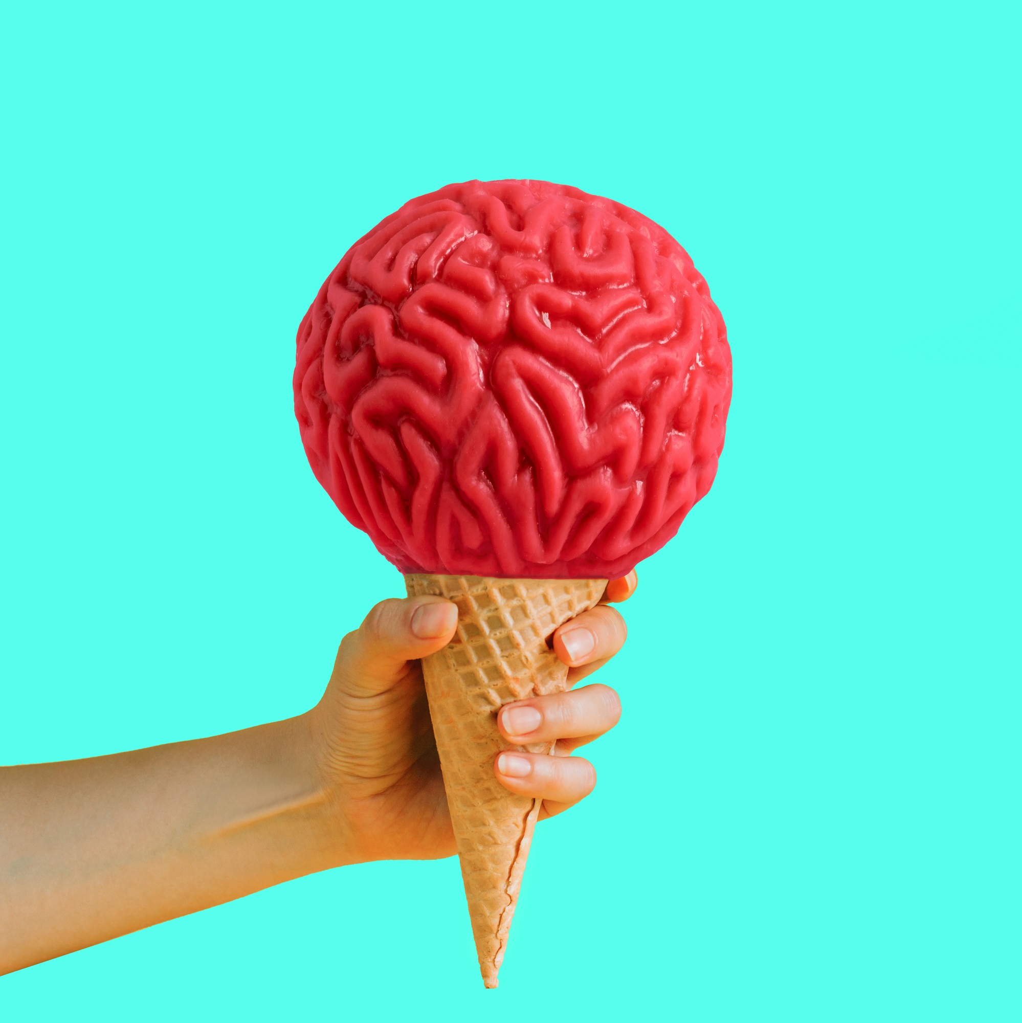 Female hand holding waffle cone ice cream with ice cream made from human brain.